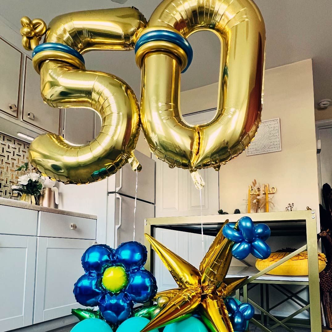 Gold balloon numbers '50' with blue and gold decorative balloons in a kitchen setting.